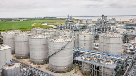 Vivergo/PA An aerial view of the facility in Saltend. There are a large metal structures and silos, along with associated pipework. There is an estuary in the background.