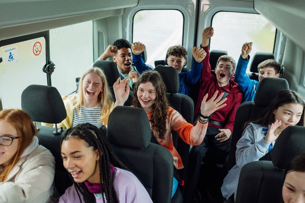 A high angle view of group of young teenage students enjoying the bus ride to a school field trip