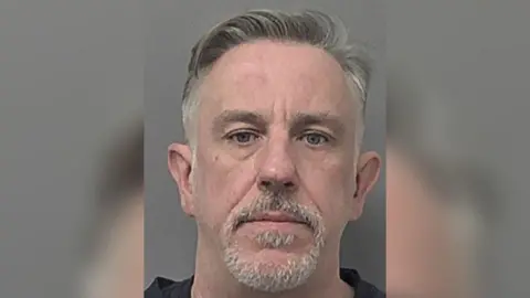 Humberside Police A police head and shoulder's photo of David Young, who has short grey hair and a short grey moustache and beard. He is looking into the camera with a serious expression.