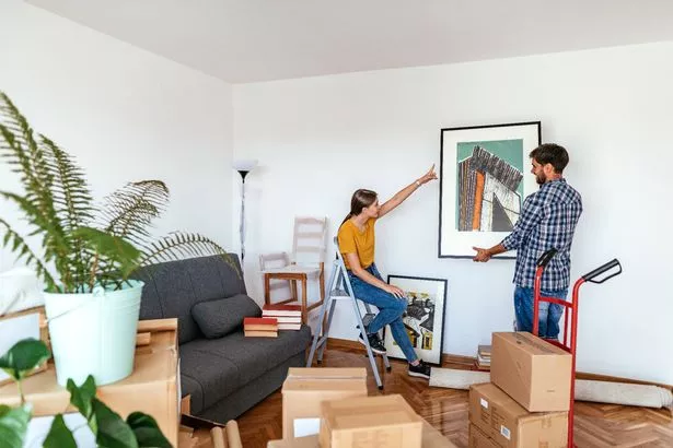 Couple moving in the new apartment, unpacking cardboard boxes and moving the furniture in