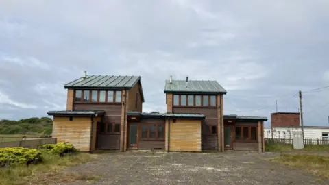 BBC / Simon Spark Two two-storey houses side by side. 