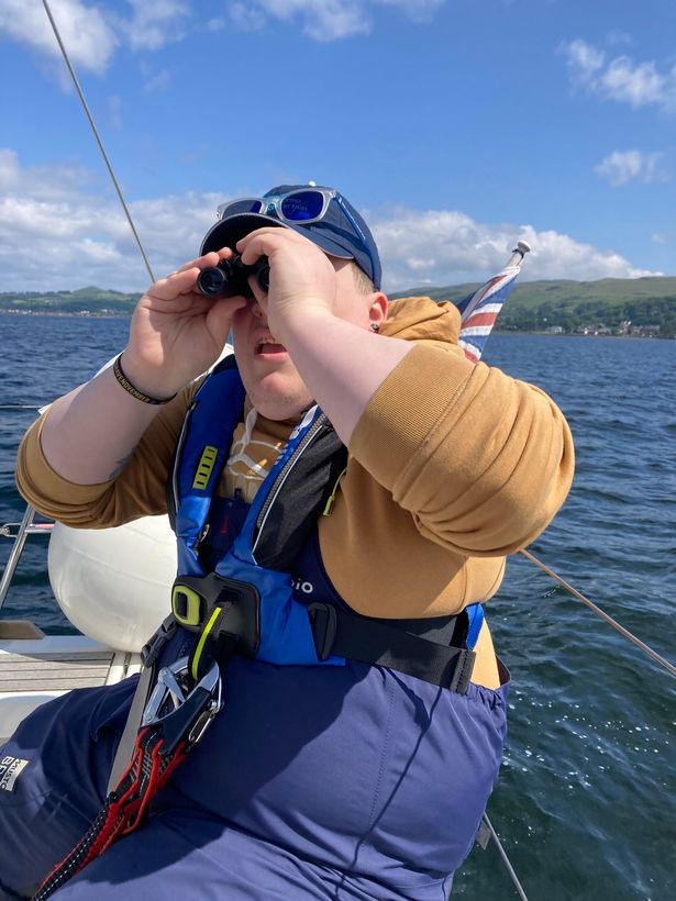 Thomas looking out to sea with binoculars