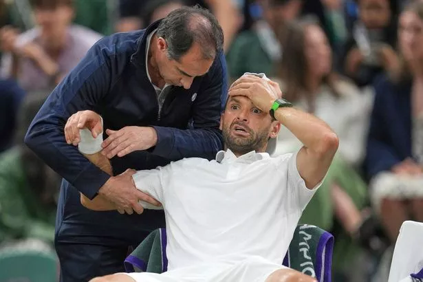 Grigor Dimitrov gets treatment after he went down with an injury which forced him to retire injured
