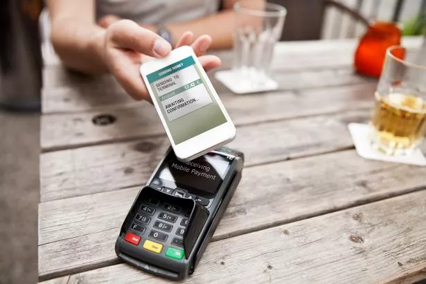 Hand with smart phone mobile paying café bill on the go
