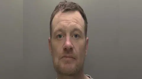 Humberside Police Police custody photograph of Timothy Tinson. He has short brown hair and beard and is wearing a grey T-shirt