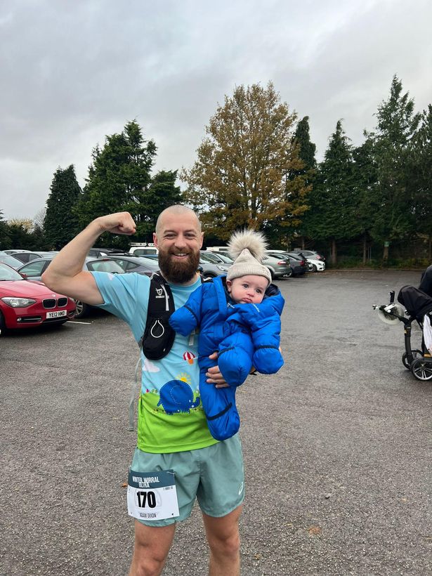 Adam Dixon holds his son Ezra after completing the Winter Wirral Ultra, a 37 mile marathon.