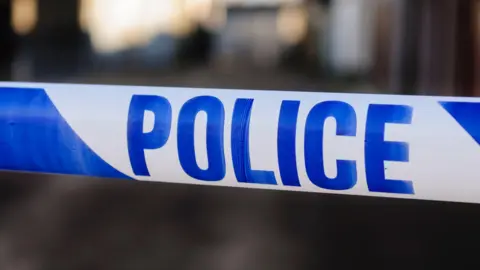 Getty Images A blue and white police cordon. The background is blurred.