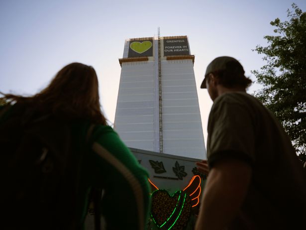 People standing in front of Grenfell Tower, ahead of a silent march in memory of those killed in the Grenfell Tower disaster, on the eighth anniversary of the fire. 