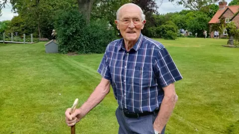 Denise Byas Richard Byas in a garden with a walking stick.