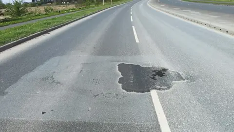 East Riding of Yorkshire Council A view of a dual carriageway road with a large, dark piece of patching in the centre line