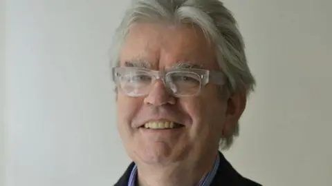 Terry Farrell, smiling in smart clothes, he has grey hair in an image from 2012