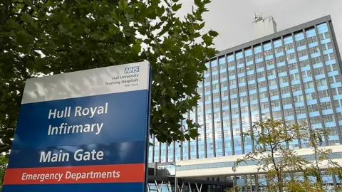 BBC Outside of Hull Royal Infirmary showing a blue hospital sign in the foreground and the main multi-storey building in the background