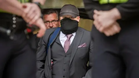 PA Media Former funeral director Robert Bush leaves Hull Crown Court, he is wearing a grey three piece suit with a purple tie and pocket square. 