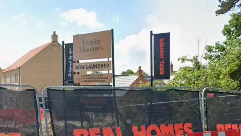 Google Barriers with Beal Homes black banners on with the branding in red. Behind are houses and a sign reading "Ferriby Meadows" and "NOW LAUNCHED" underneath. The sky is blue and dotted with clouds.