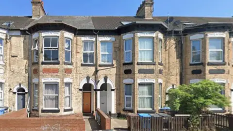 Google A street of Victorian terraced houses with pale brick fronts and two-storey bay windows. There is graffiti on the wall of one of the properties. The image is taken from Google Streetview. 