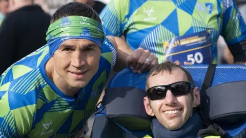 PA Media Kevin Sinfield (left), and Rob Burrow, smiling together at the start line of a race, wearing racing clothing.