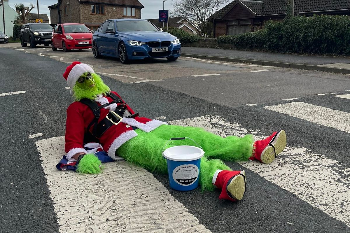 The Grinch - aka Dave Gelder - takes a rest on a zebra crossing during his marathon fundraiser