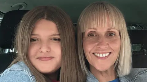 PA Media A mother and daughter pose for a selfie inside a car