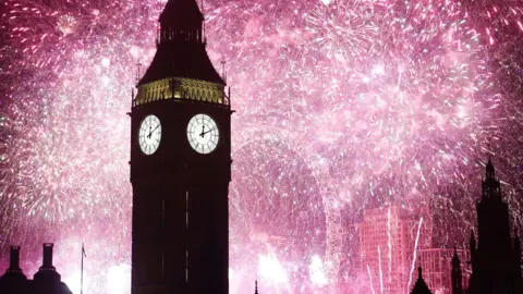 PA Media The Elizabeth Tower, better known as Big Ben, is silhouetted against bright pink fireworks exploding against the night sky in central London, with the London Eye and rooftops in the background. The white clock face on the tower reads 00:11.