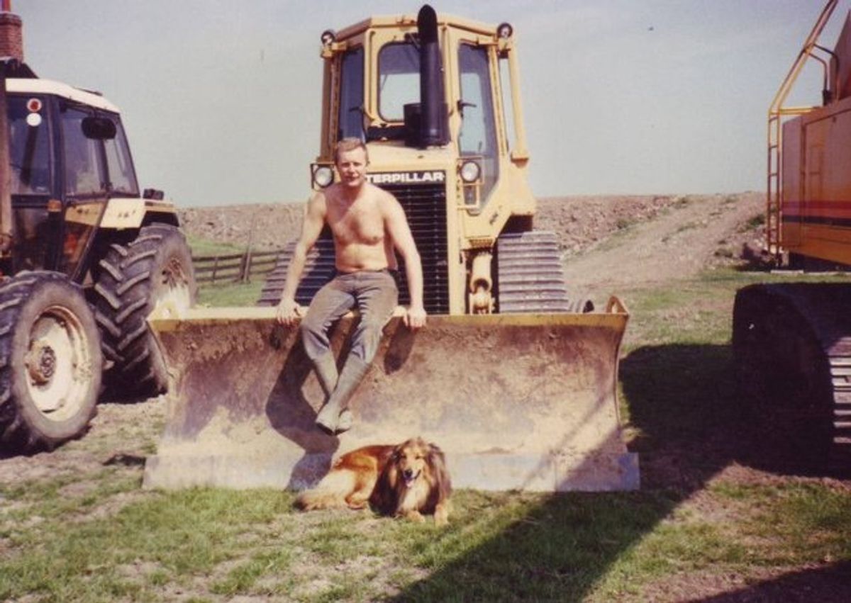 A man and a dog sitting with some machinery. 