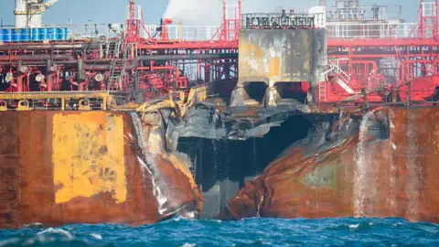 PA Media A picture shows a large hold in the side of a fire damaged oil tanker in the North Sea.