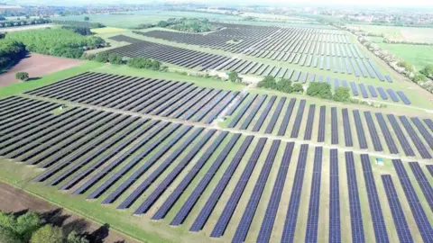 Boom Power An artist's impression of a solar farm with hundreds of solar panels sited in open countryside 
