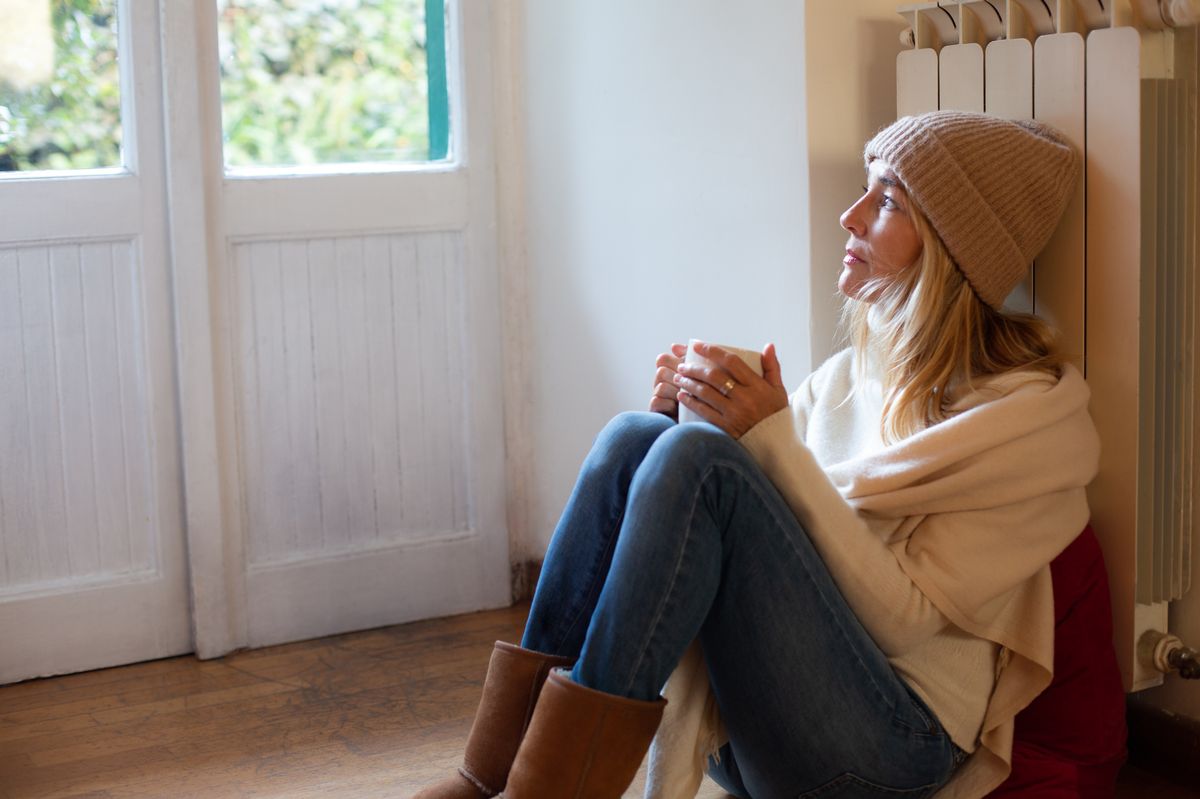 Woman sat near radiator in home