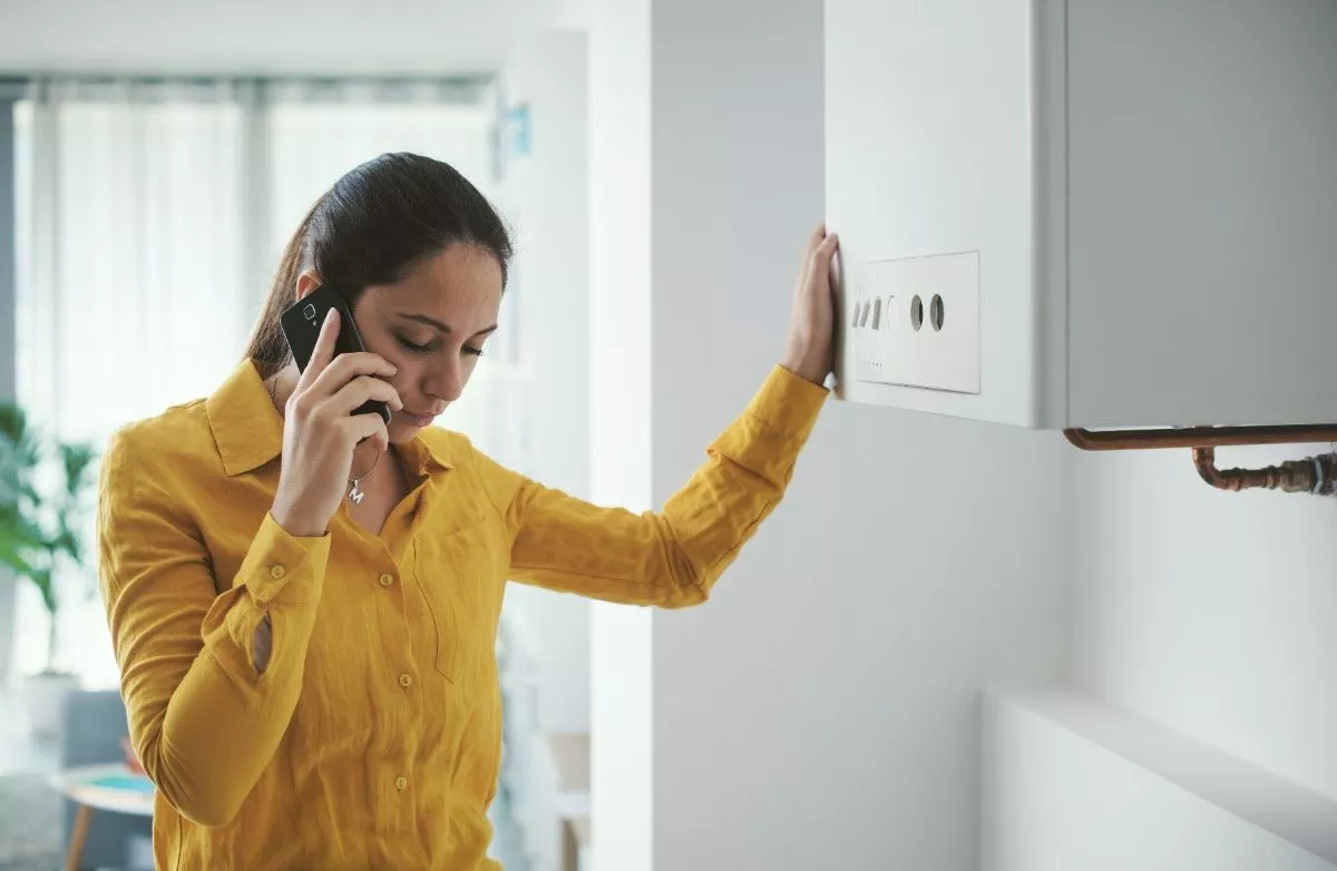 Woman on phone standing next to boiler
