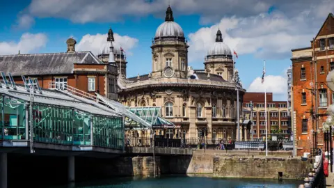 Getty Images A waterfront scene with a glass walkway on the left and buildings in the distance. 