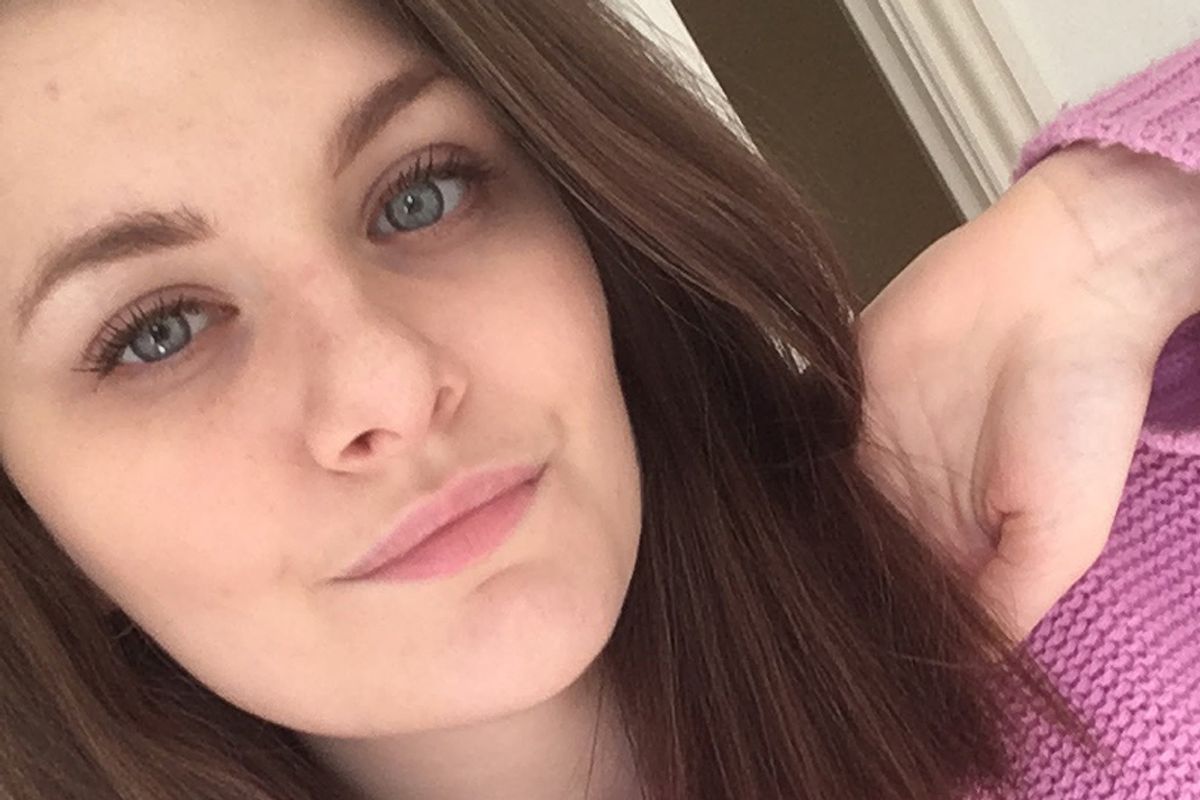 A young woman pouts whilst taking a photo of herself