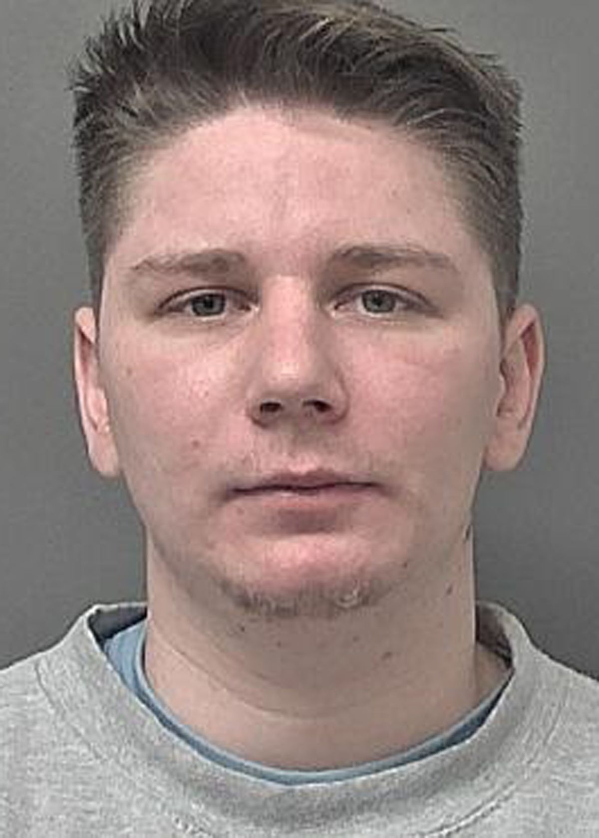 A mugshot of a man in a grey jumper