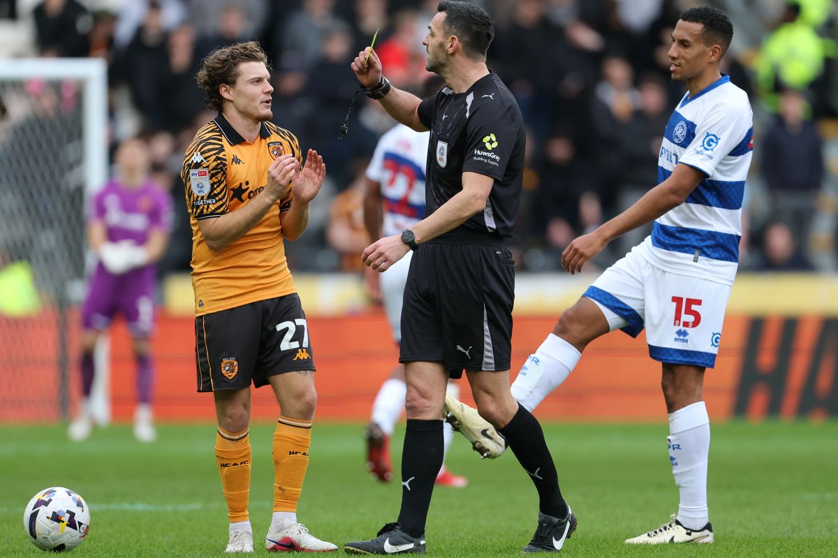 Referee Andrew Madley shows a yellow card to Hull City's Regan Slater
