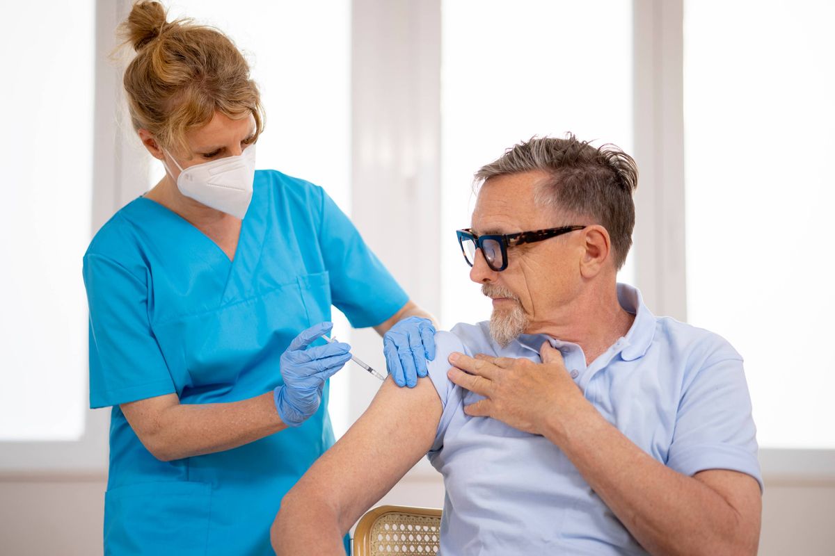 active senior gets flu shot vaccinated with syringe by female doctor