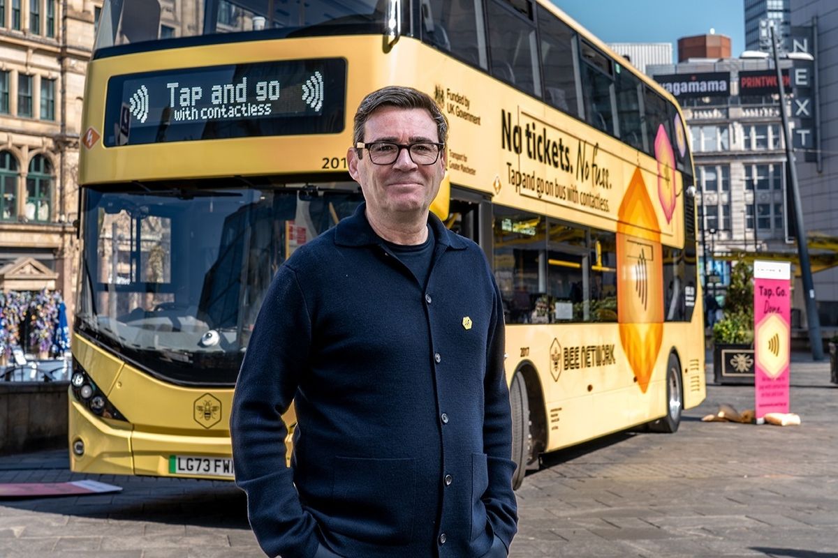 Mayor of Greater Manchester, Andy Burnham stands in front of a Bee Network bus