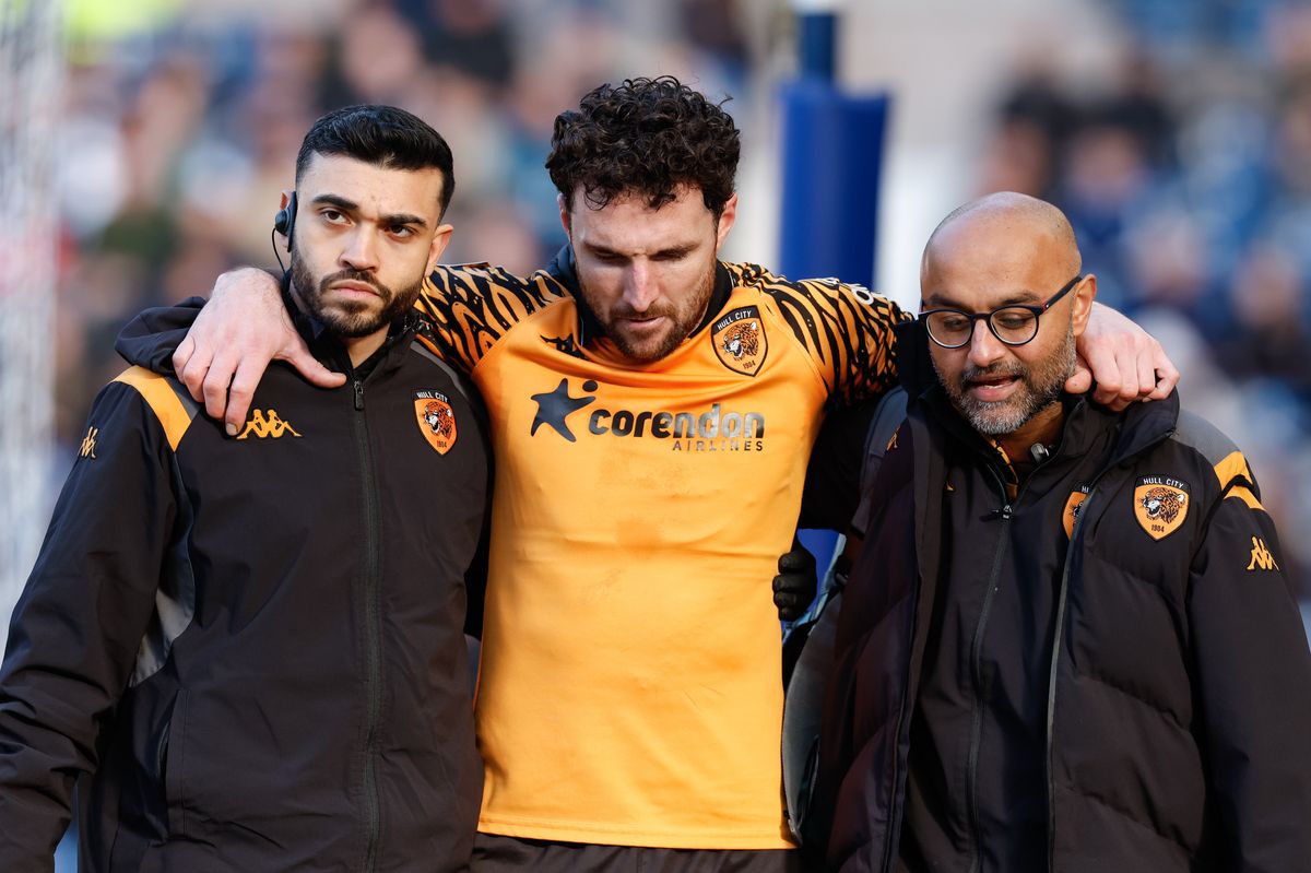 Lewie Coyle is helped off the pitch by Hull City's medical staff