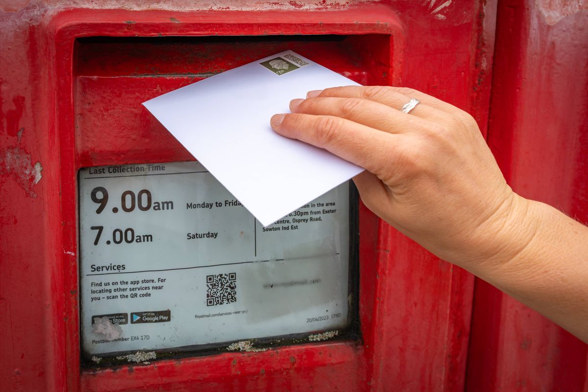 Exeter, United Kingdom, 30.09.2024, Posting a Letter to a Classic Red British Post Box