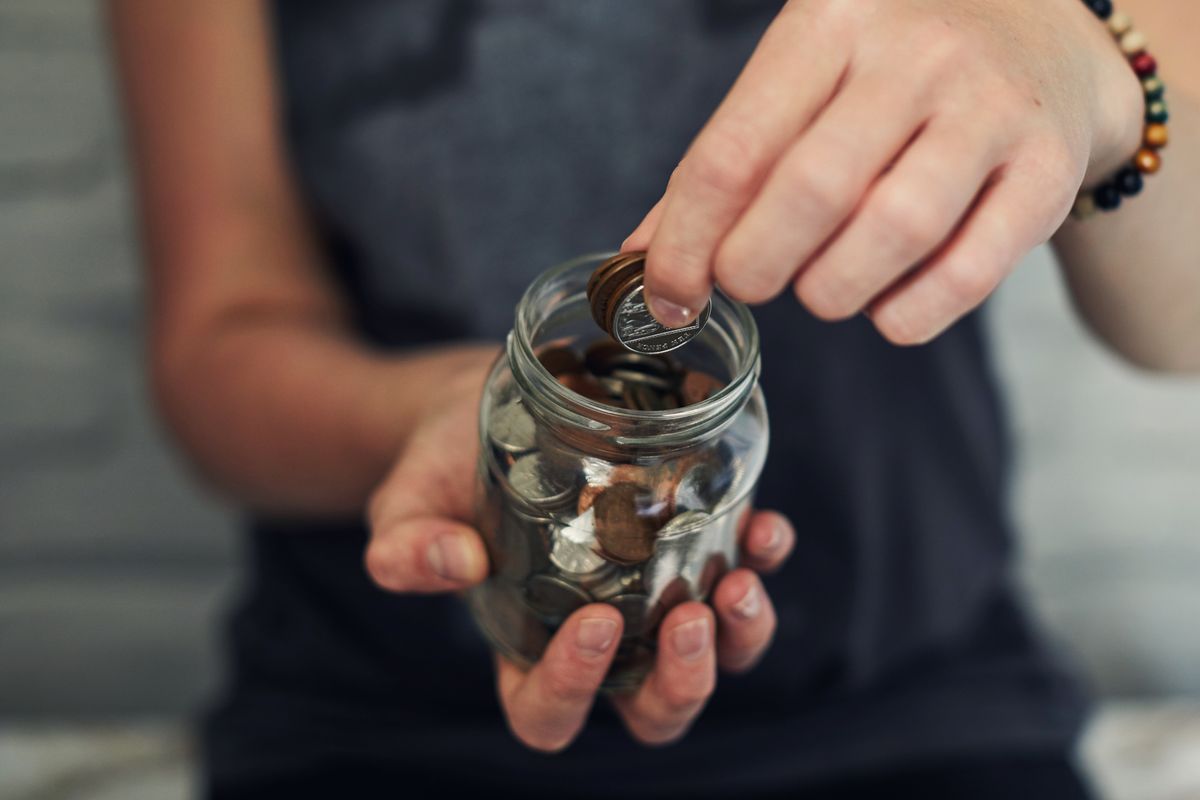 Young woman putting money into a jar