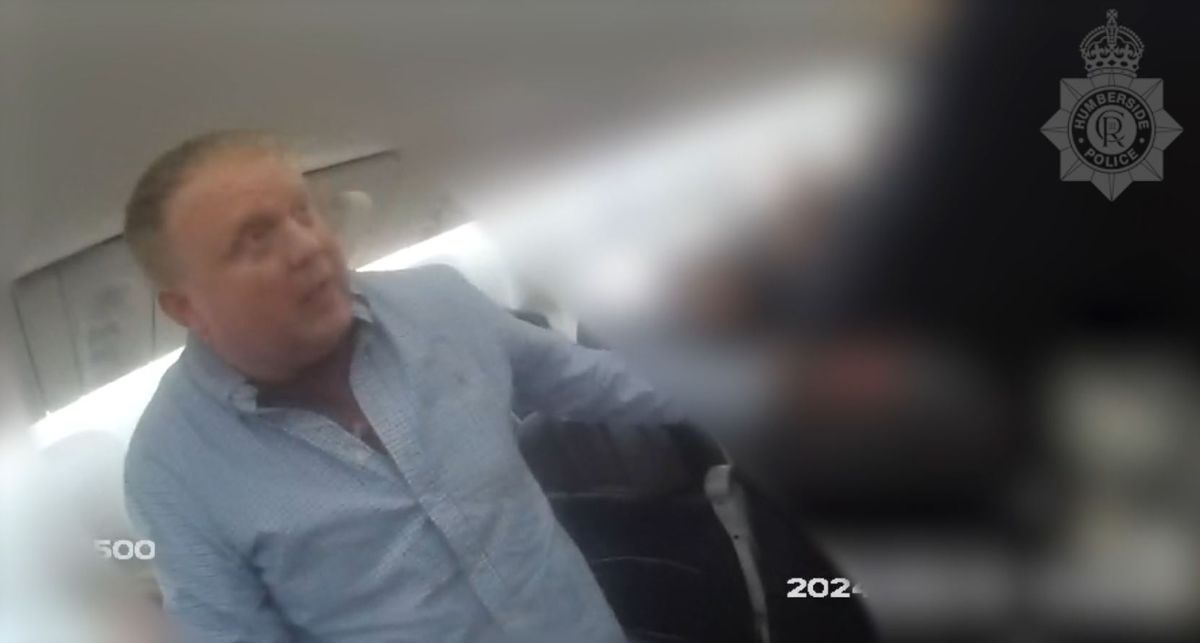Robert Bush looks surprised as he is asked to accompany the police off the plane