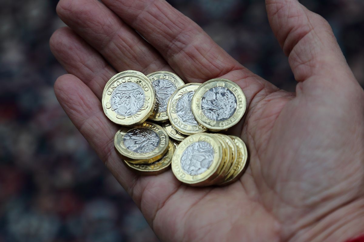 Pensioner holding one pound coins in hand.