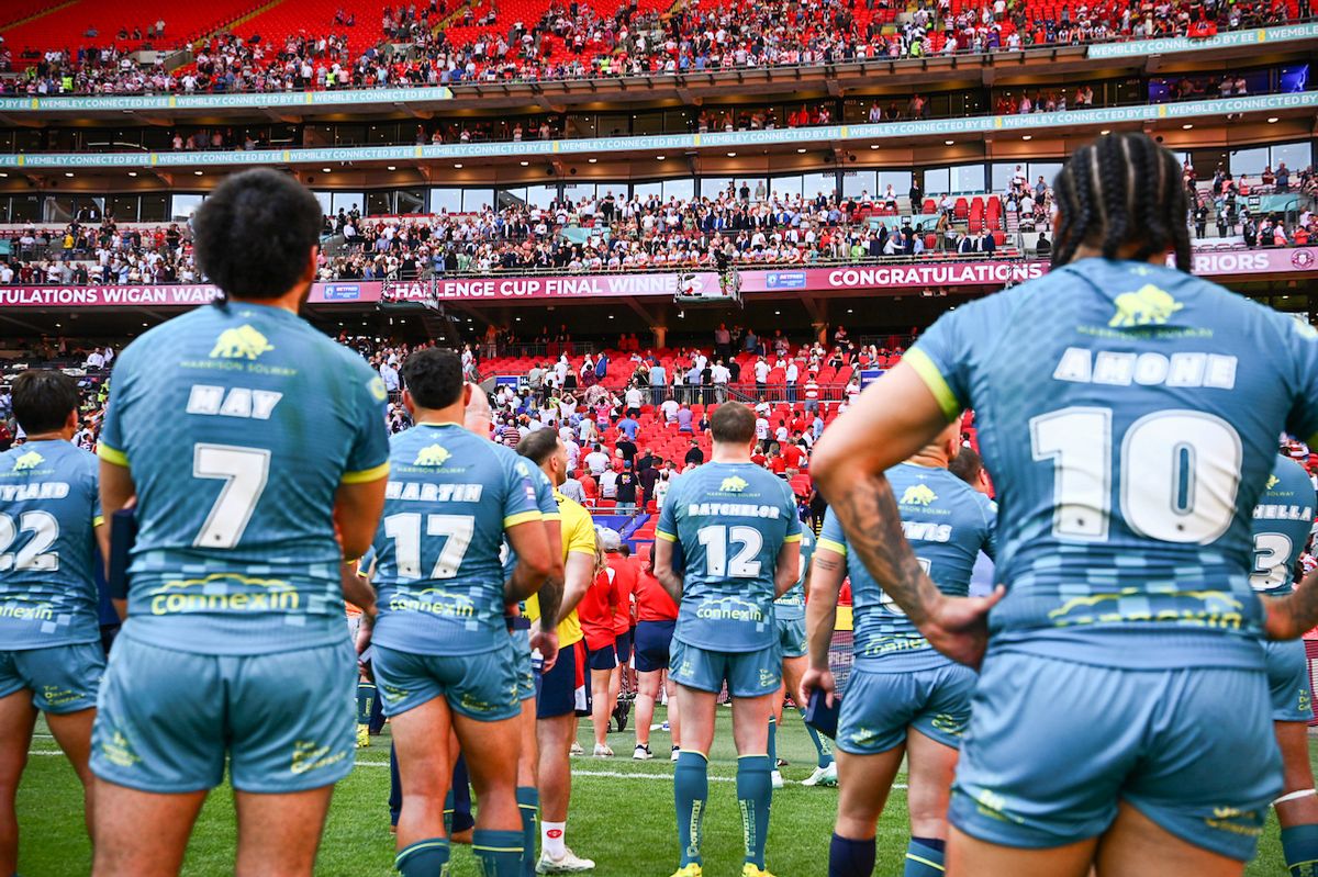 Hull KR look on in dejection as Wigan lift the Betfred Challenge Cup trophy.
