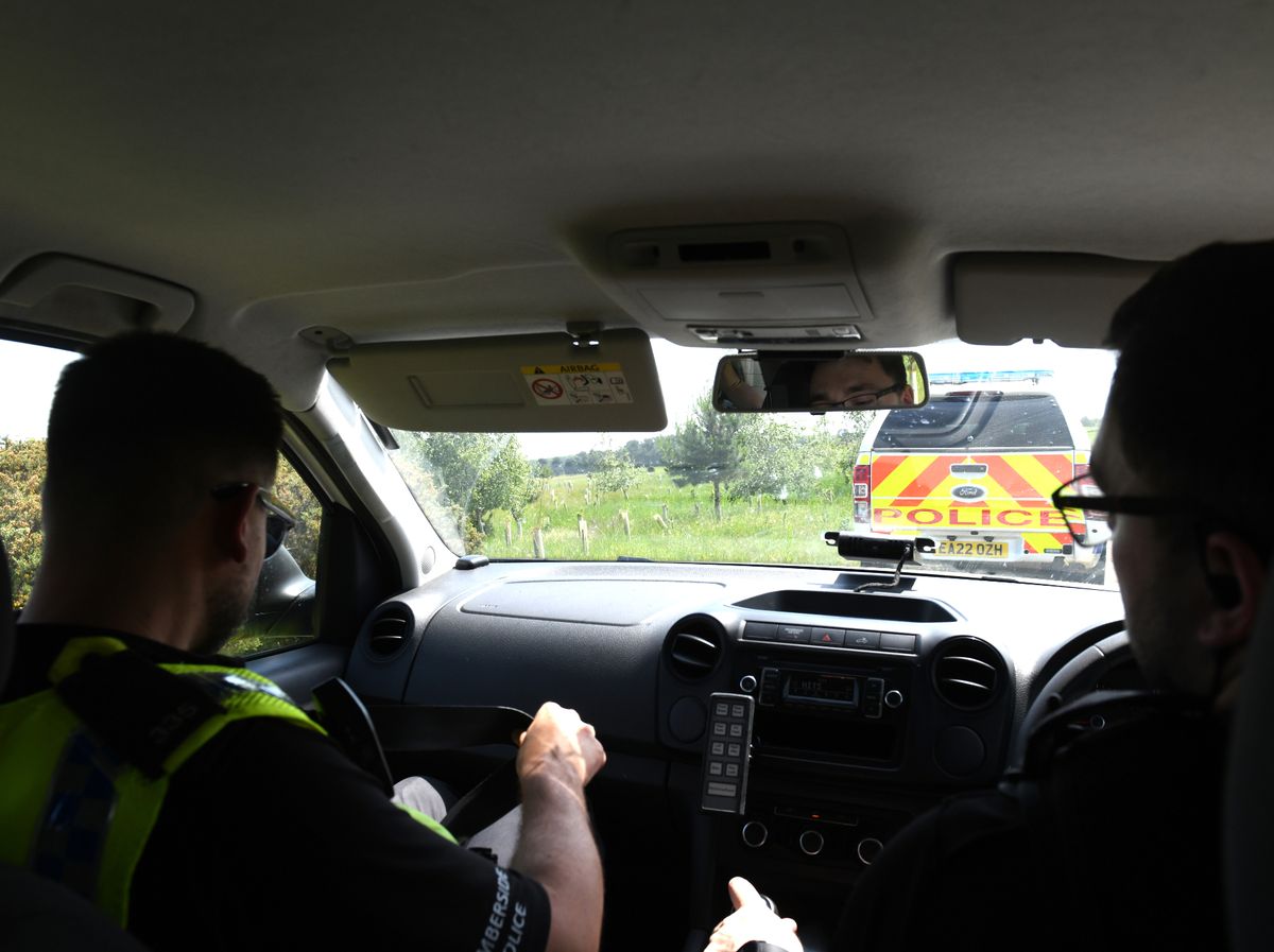 Humberside Police officers head towards the edge of a field on a farming track to deploy a drone to check for nuisance motorbike riders in a quarry near Scunthorpe steelworks