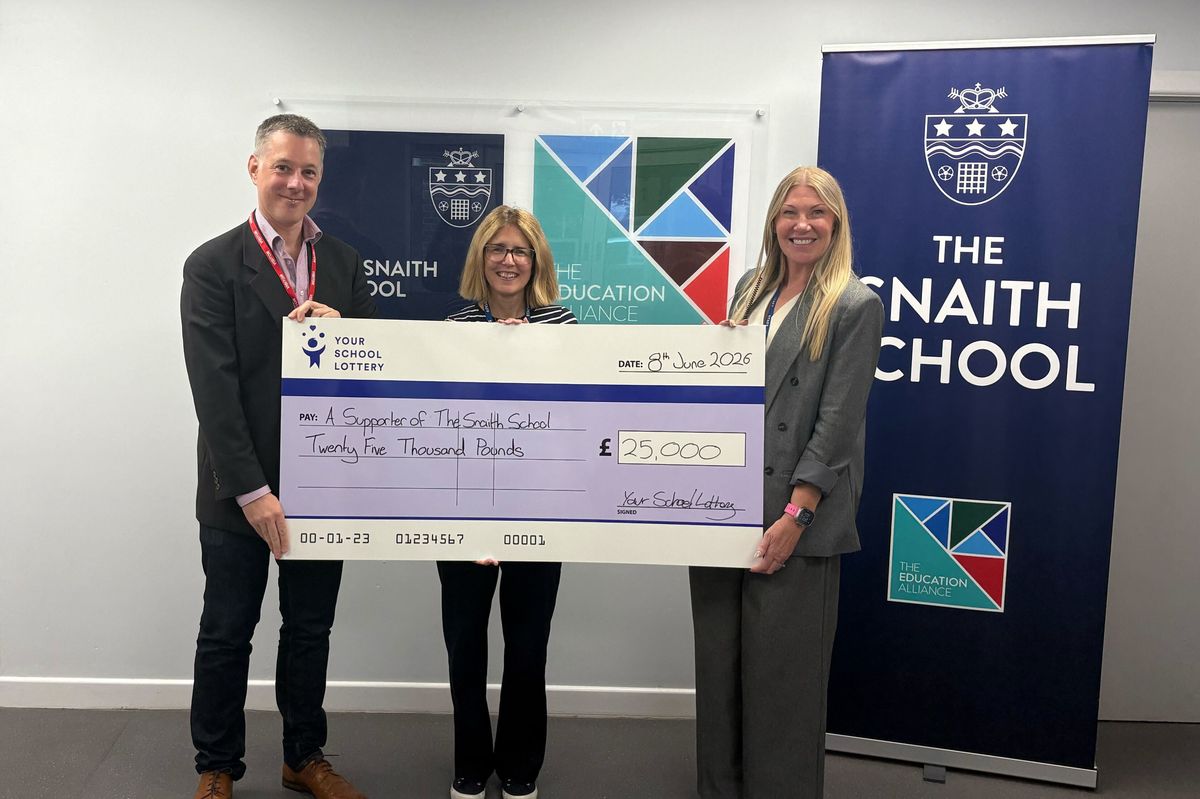 Three staff members stand in front of a Snaith School banner holding a cheque for £25,000