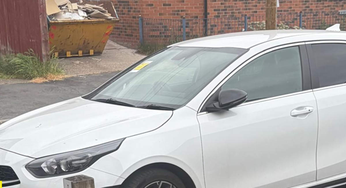 A ticket on the dashboard of a white car