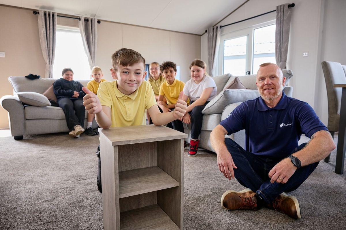 Pupils are pictured proudly showcasing a bedside table which they helped to build alongside Willerby’s production manager, Glenn Craig