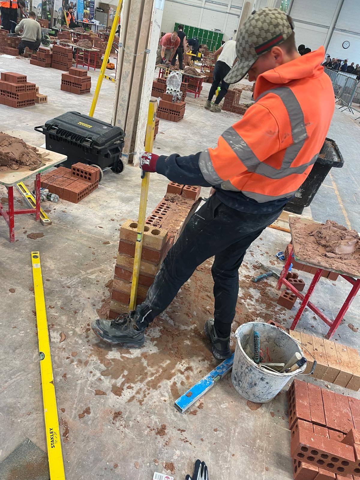 Amelia Kokosa holds a spirit level against a brick wall in a warehouse where she was competing in the Golden Trowel Finals in Leeds