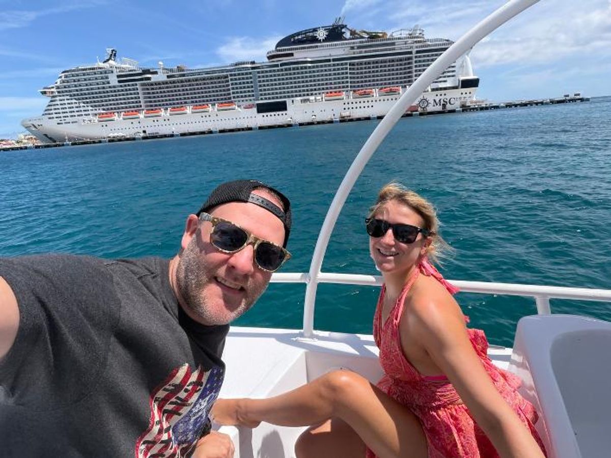 James and Maddy on a boat with a cruise liner in the background