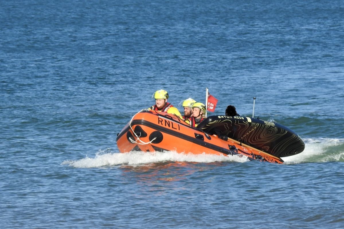 A paddleboarder in the lifeboat with the RNLI volunteer crew and his paddleboard