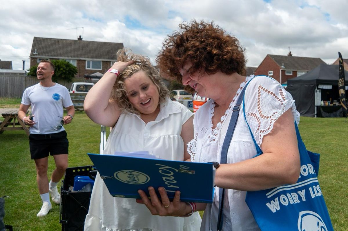 Two members of Hull's Lucy's Pop Choir with instructor Carl in the background